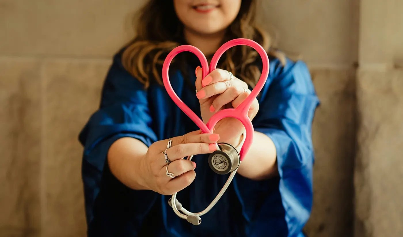 Nurse holding a pink stethoscope in a heart shape